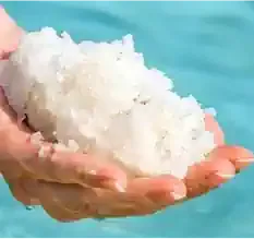 Mineral salt held in hand at the water's edge